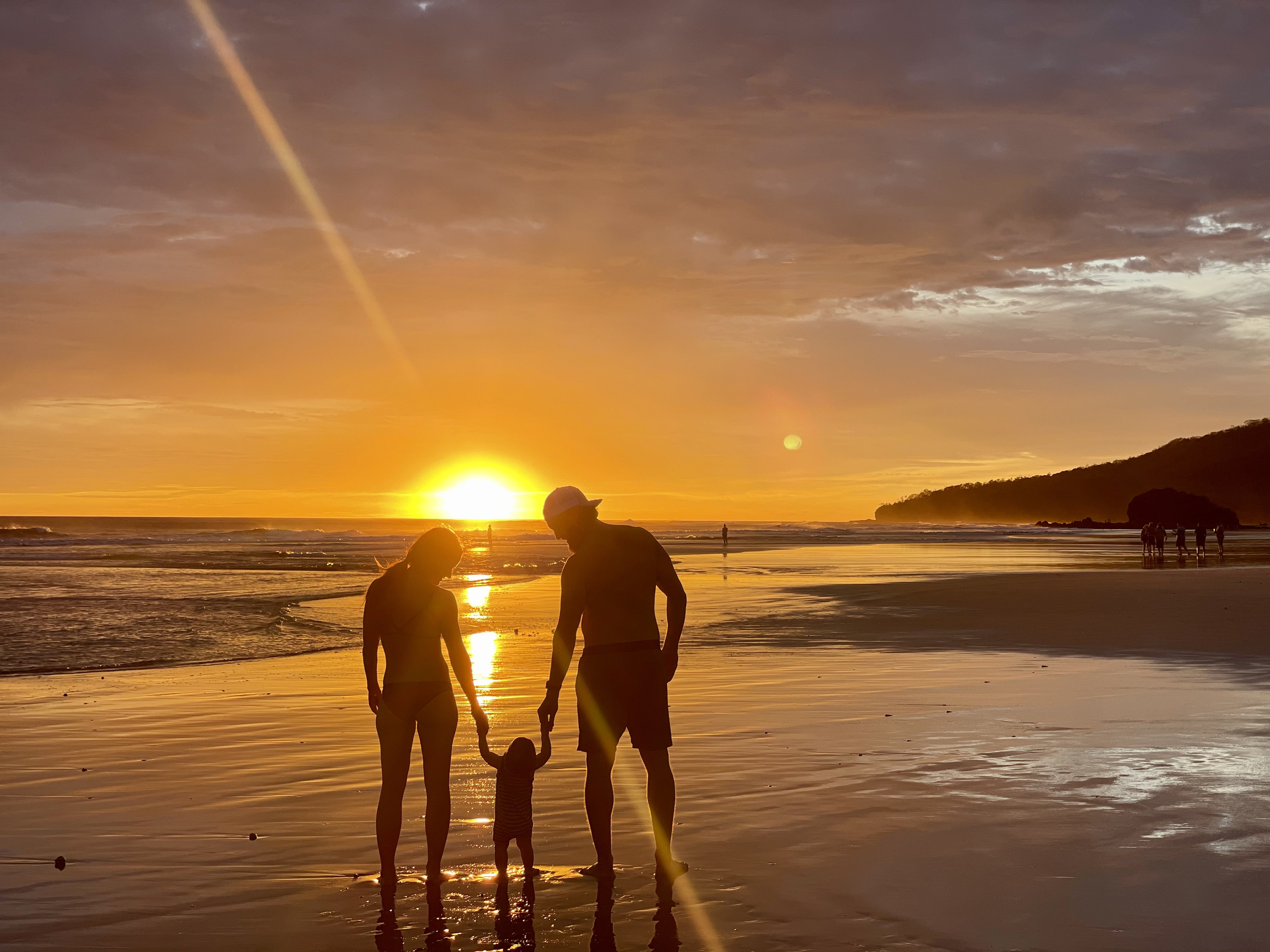 Family walk on the beach at sunset