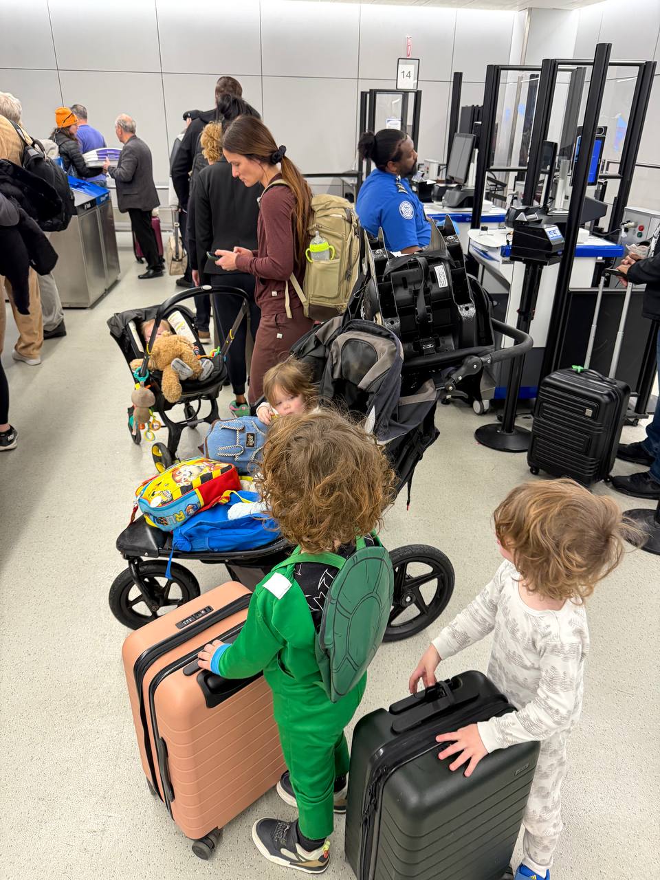 Family navigating TSA with four kids and luggage