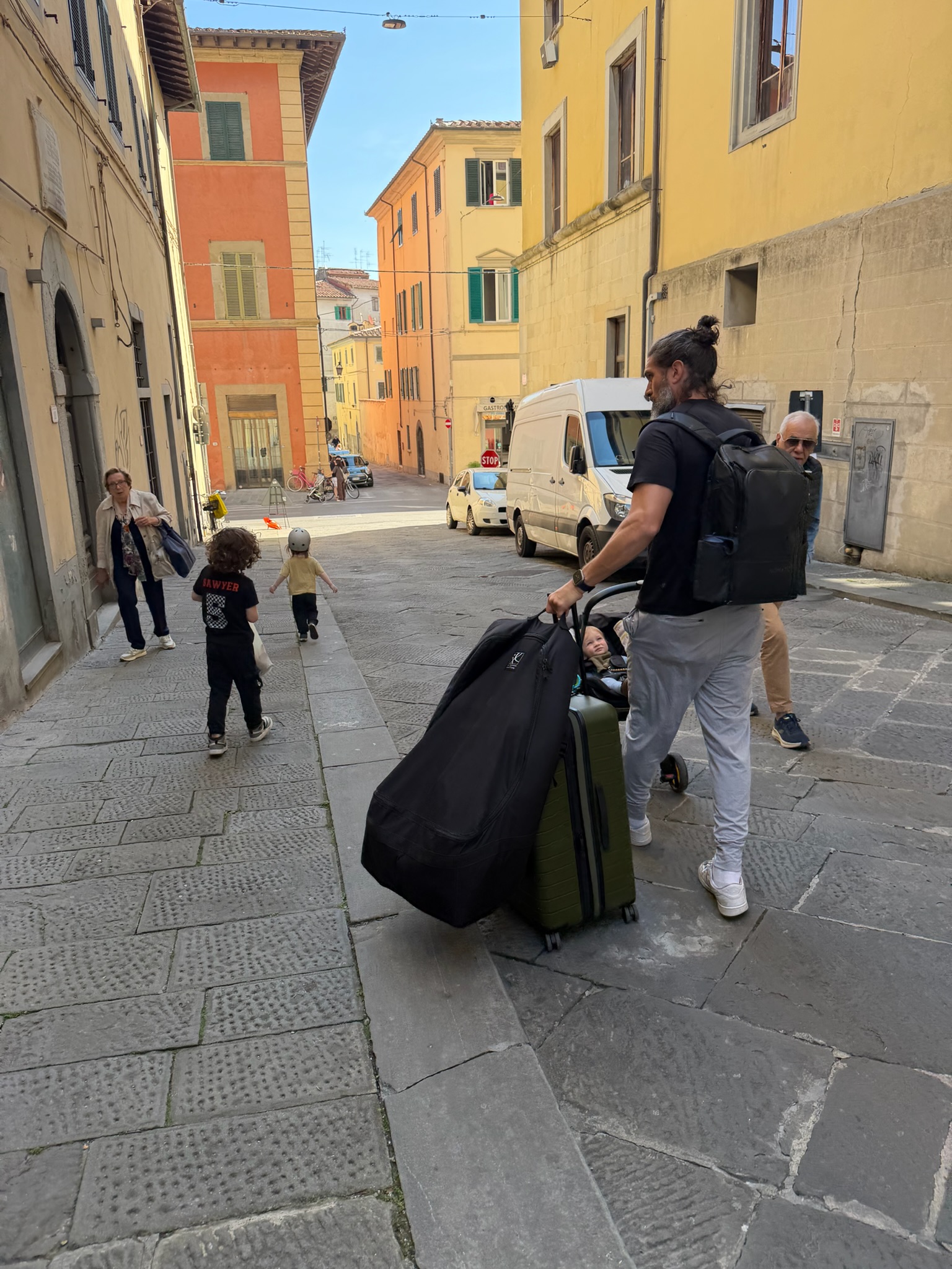Chris walking through Pistoia streets with luggage and stroller