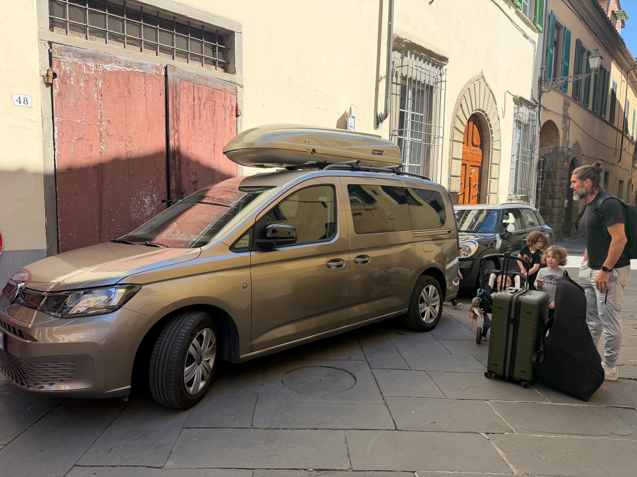 Family loading into rental VW van with roof box